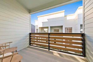 Un balcon avec une balustrade en bois, une petite table et des chaises.
