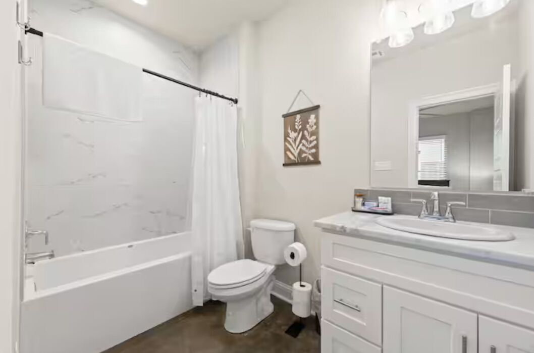 A bathroom with a bathtub, toilet, sink, and mirror.