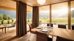 A dining area with a table set for four, a sofa, and curtains. - RACING Suite – Terrace & Sauna Access (Kleinboden)