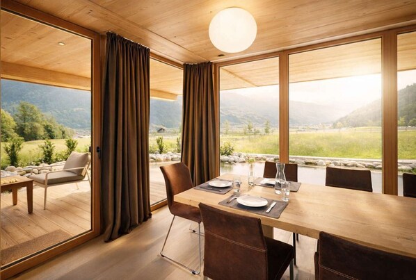 A dining area with a table set for four, a sofa, and curtains. - RACING Suite – Terrace & Sauna Access (Kleinboden)