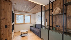 Ein modernes Interieur mit Holzboden, einem grauen Sofa, einem runden Tisch und eingebauten Regalen mit Dekoration.