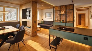 Ein modernes Interieur mit einer Holztischlerei, einer Küche mit integrierter Kochinsel und einem Wohnbereich mit Sofa und Kamin.