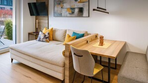 A modern living room with a sofa, a dining table, and a TV. - ROFANLODGE Gutschlhofer – A house with a view, a terrace and parking (Mariatal)