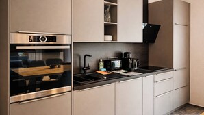 Eine moderne Küche mit integrierten Geräten, einem Essbereich und fest installierten Regalen.
