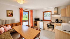 Cocina compacta con comedor, televisor y vista al exterior.