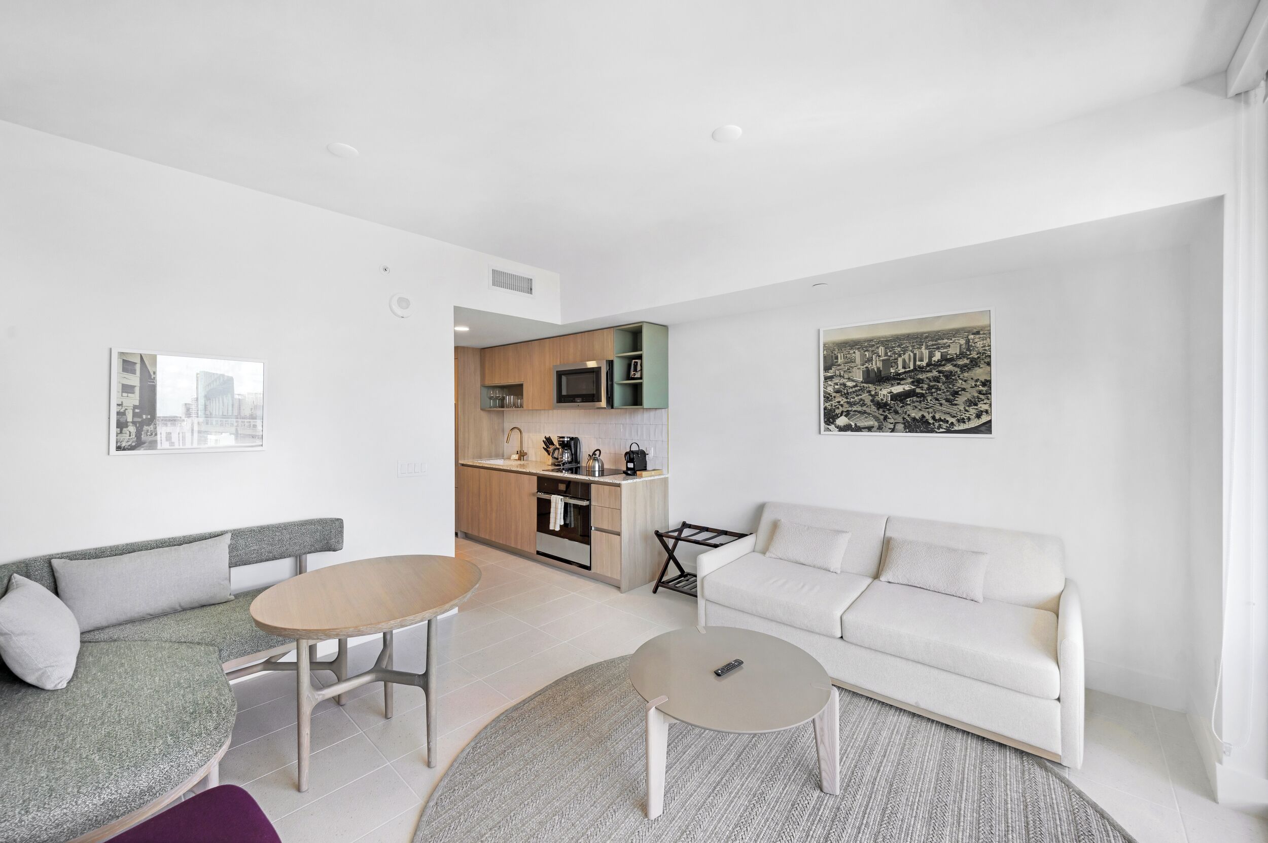 A modern living room with a sofa, a round coffee table, and a dining table.