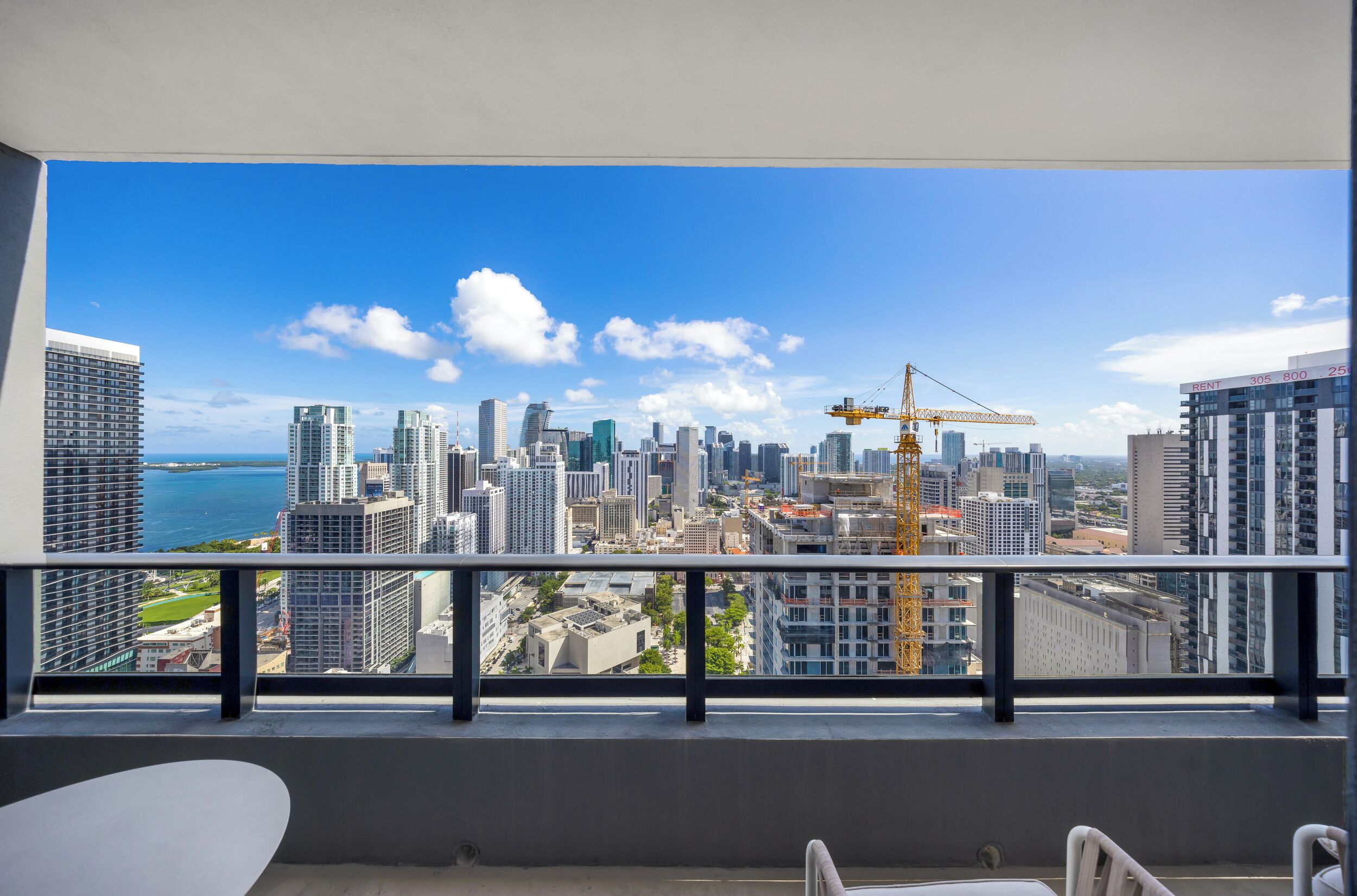 A balcony with a city view, a crane, and high-rise buildings.
