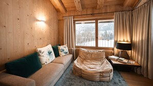 Ein gemütlicher Raum mit Holzwänden, einer Couch, einem Sitzsack, einer Lampe und einem Fenster mit Vorhängen.