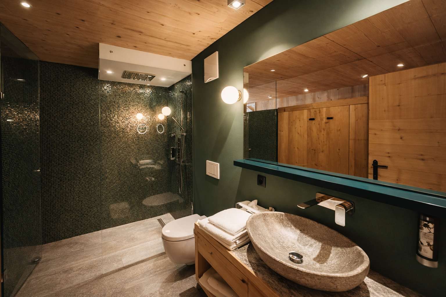 Ein modernes Badezimmer mit einer gläsernen Duschkabine, einem hölzernen Waschtisch und einem großen Spiegel.