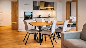 A modern kitchen with white cabinets, a wooden dining table, and grey upholstered chairs. - CHEZ NOUS – Balcony & Mountain View (Fügen)