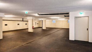 A spacious underground parking area with concrete floors, white walls, and emergency exit signs. - CHEZ NOUS – Balcony & Mountain View (Fügen)