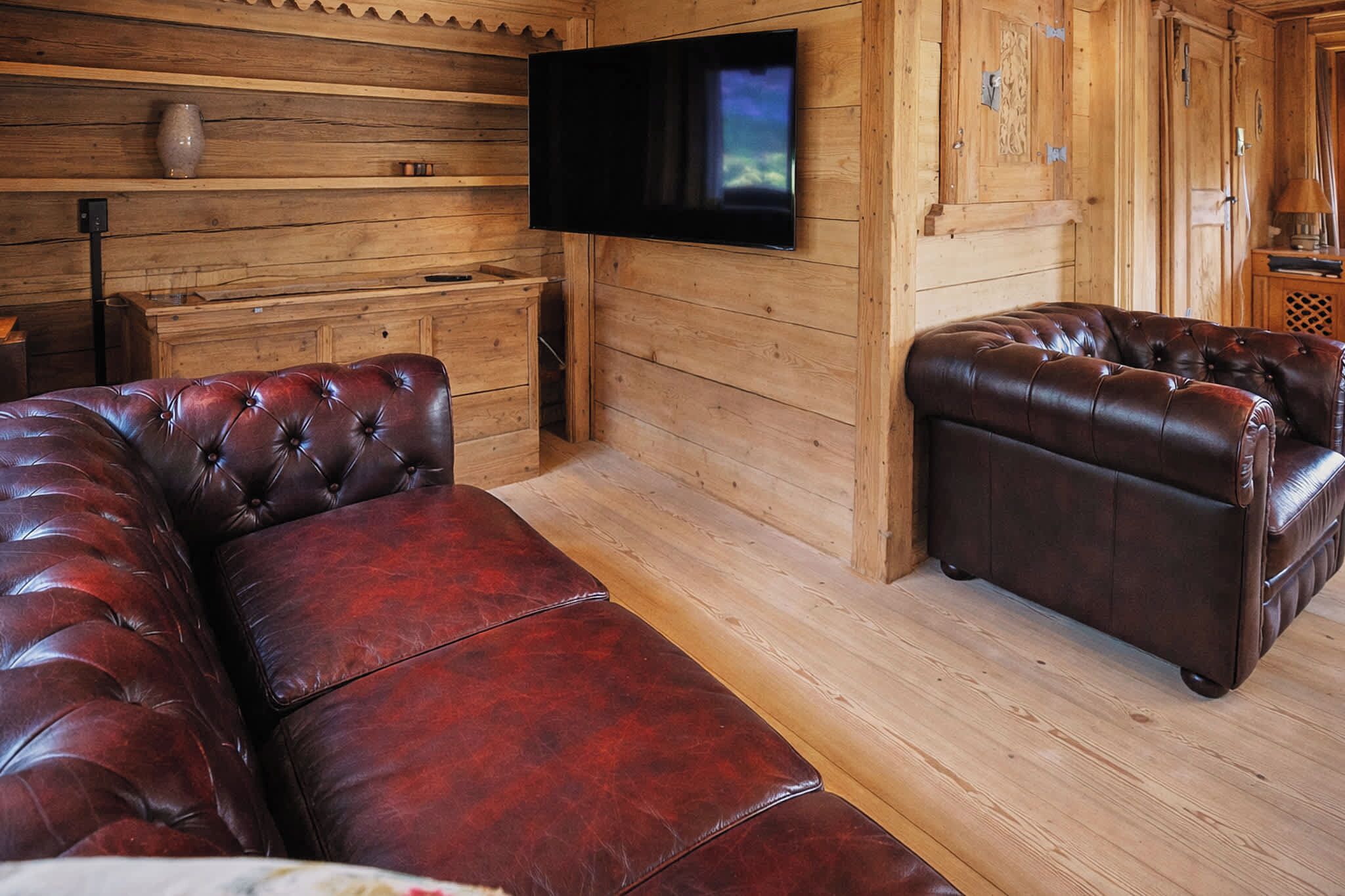 Un interior de madera con un sofá de cuero, un televisor de pantalla plana y un armario de madera.