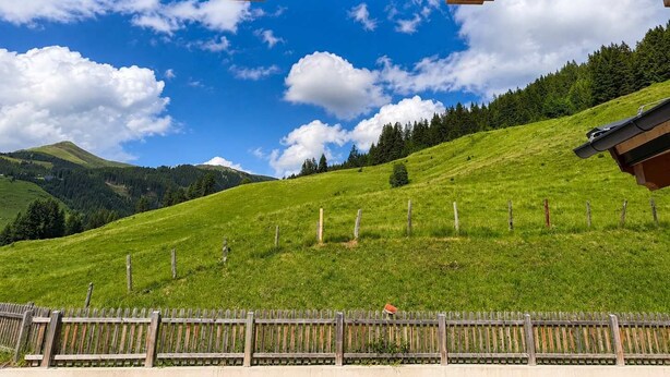 A wooden structure with a view of a green hillside and a clear sky. - BEIM LOIS Edelweiss – with Sauna Access (Gerlos)