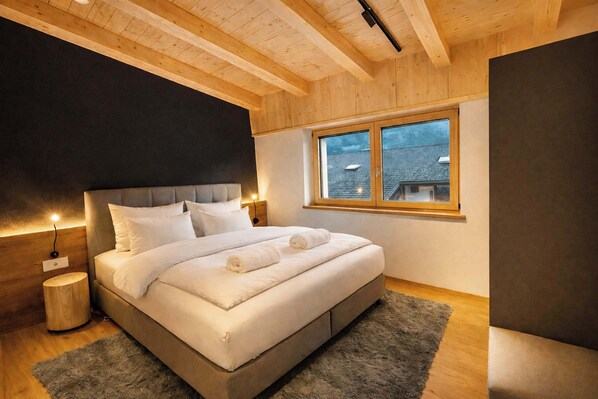 A bedroom with a bed, bedside tables, a window, and a wooden ceiling. - GLETSCHERBLICKSTUBE – Terrace & Mountain View (Fügen)
