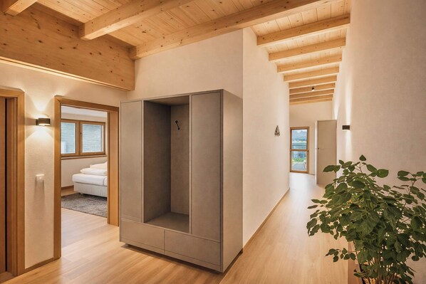 A modern interior with wooden beams, a large wardrobe, a plant, and a view through a window. - GLETSCHERBLICKSTUBE – Terrace & Mountain View (Fügen)