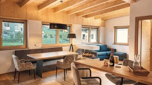 A modern interior with a wooden ceiling, a dining area with a table and chairs, a sofa, and a fireplace. - ViVaZILARE – Design Loft with Terrace (Fügen)