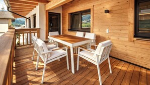 A wooden deck with a table and chairs, large windows, and a view of the outdoors. - ViVaZILARE – Design Loft with Terrace (Fügen)