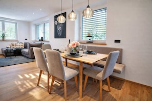 A modern dining area with a wooden table, grey upholstered chairs, and pendant lighting.