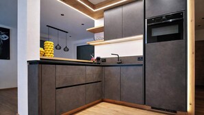 Et moderne køkken med indbyggede hårde hvidevarer, trædetaljer og et minimalistisk design.