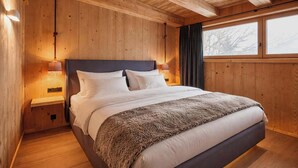 A wooden-paneled bedroom with a bed, nightstands, and a window. - GOLF Suite – Penthouse, Balcony & Sauna Access (Kleinboden)