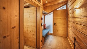 A wooden interior with a bench, a fire extinguisher, and a door leading to another room. - GOLF Suite – Penthouse, Balcony & Sauna Access (Kleinboden)