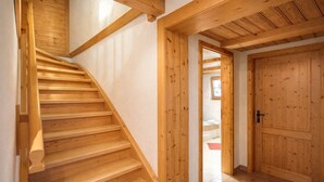 Una scala in legno conduce a una camera da letto con un'ampia porta di legno.