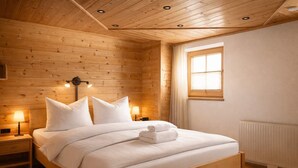 Una camera da letto con rivestimento in legno, un letto, lampade da comodino e una finestra.