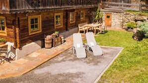 Una baita di legno rustica con patio, due poltrone e un tavolo.