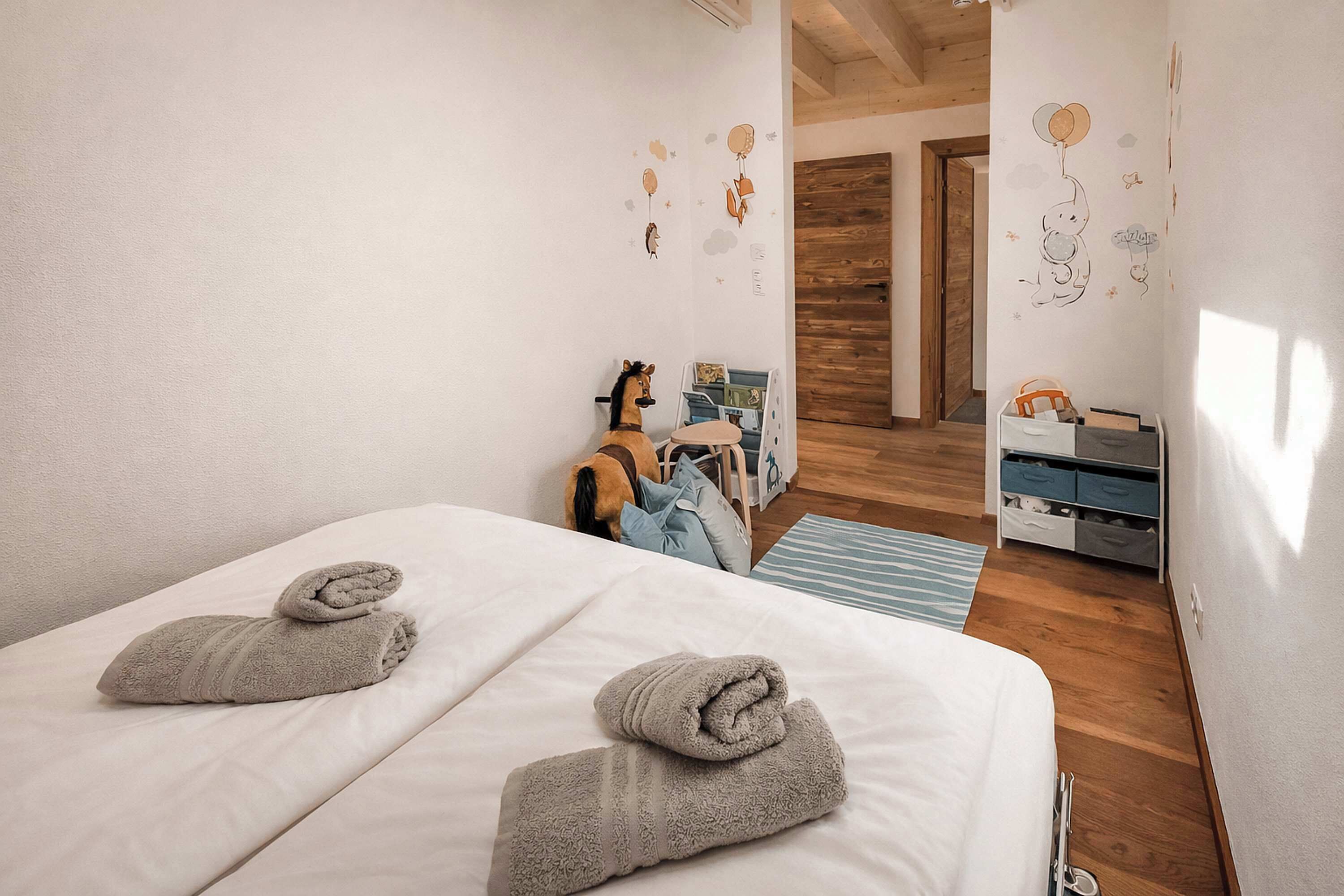Une chambre avec deux lits, un plancher en bois, une porte et un mur décoré d’autocollants.