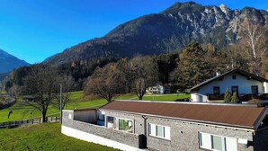 Ein Haus mit geneigtem Dach, einem Steinuntergrund und einem großen Fenster.
