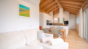 Ein modernes Interieur mit einem weißen Sofa, einem Esstisch und einer Küchenzeile.