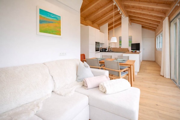 A modern interior with a white sofa, dining table, and kitchen area.