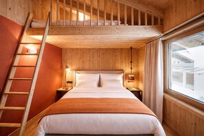 Ein Zimmer aus Holz mit einem Bett, einer Leiter und einem Fenster.