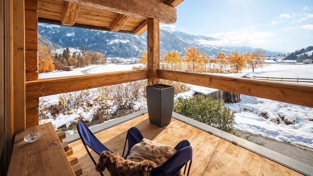 Eine Holzterrasse mit Blick auf schneebedeckte Berge und einen klaren Himmel.