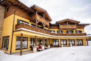 Ein mehrstöckiges Gebäude mit Holzbalkonen und großen Fenstern, umgeben von Schnee.