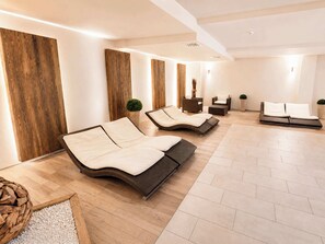 Ein Spa-Raum mit zwei Liegesesseln, einem kleinen Tisch und einer an der Wand befestigten Massageliege.