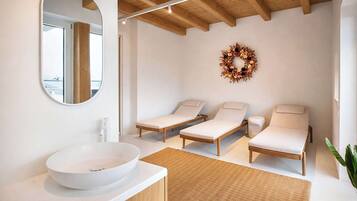 Ein modernes Badezimmer mit einem großen, ovalen Waschbecken, zwei Liegen, einem Spiegel und einer Holzzahl.