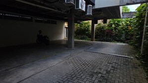 A covered parking area with a motorcycle, concrete pillars, and a paved walkway. - Merepe Suites 103 by La Playa (Ipojuca)