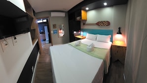 A hotel room with a bed, bedside lamps, a TV, and a wooden nightstand. - Merepe Suites 103 by La Playa (Ipojuca)