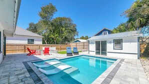 Ein Garten mit Schwimmbecken, roten Stühlen und einem Holzzaun.