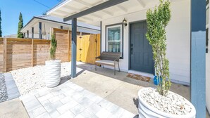Ein Haus mit überdachter Veranda, Holzzaun und Topfpflanzen.