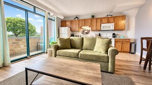 A modern living room with a sofa, a coffee table, and a kitchen area with cabinets and appliances.