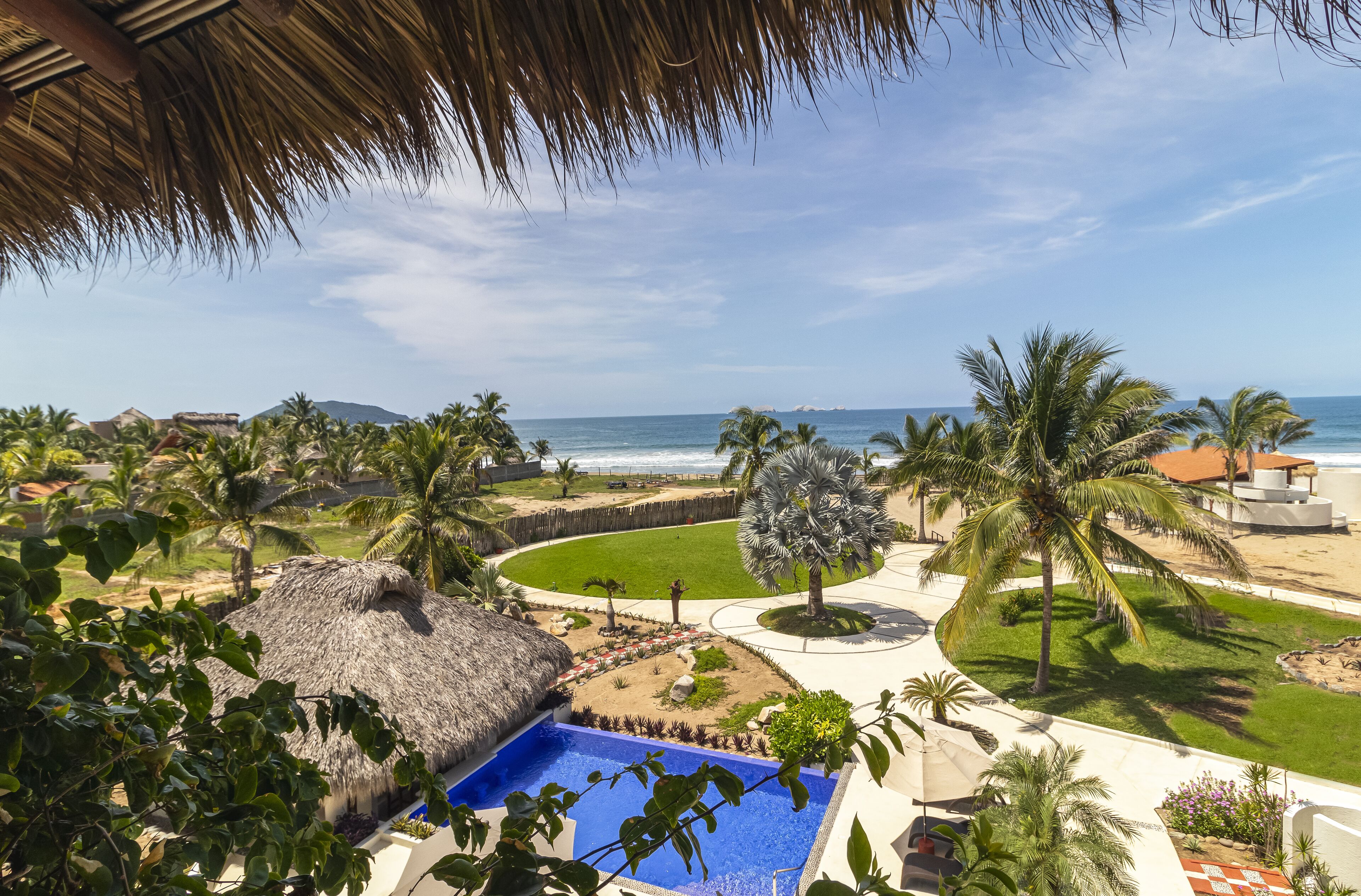 Una piscina con vista a la playa y palmeras.