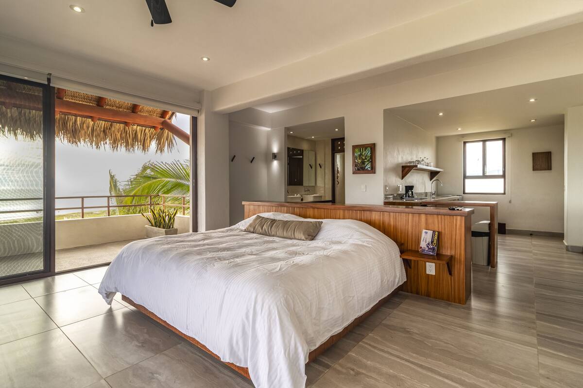Een moderne slaapkamer met een groot bed, een houten bureau en een balkon met uitzicht.