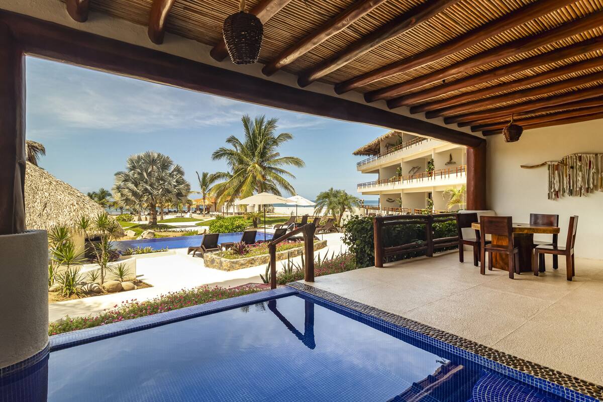 Zwembadterras met uitzicht op een resort, inclusief een zwembad, ligbedden en een eethoek.