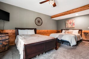A bedroom with two beds, a wooden ceiling, a mounted TV, and a wall-mounted artwork. - Starr & Sky Lodge | Hocking Hills, Hot Tub, Sauna (Logan)
