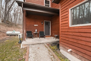 A wooden cabin with a porch, a door, and a window. - Starr & Sky Lodge | Hocking Hills, Hot Tub, Sauna (Logan)
