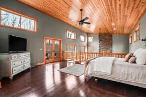 A spacious bedroom with a large bed, wooden ceiling, and multiple windows. - Starr & Sky Lodge | Hocking Hills, Hot Tub, Sauna (Logan)