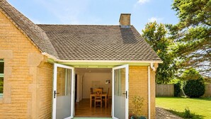 Une maison avec un patio, un coin repas et un jardin.