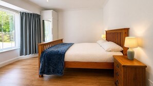 Une chambre à coucher avec un lit, des lampes de chevet, une table de chevet en bois et une fenêtre avec des rideaux.